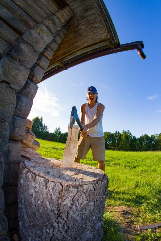 A man standing next to a wooden structure in a field