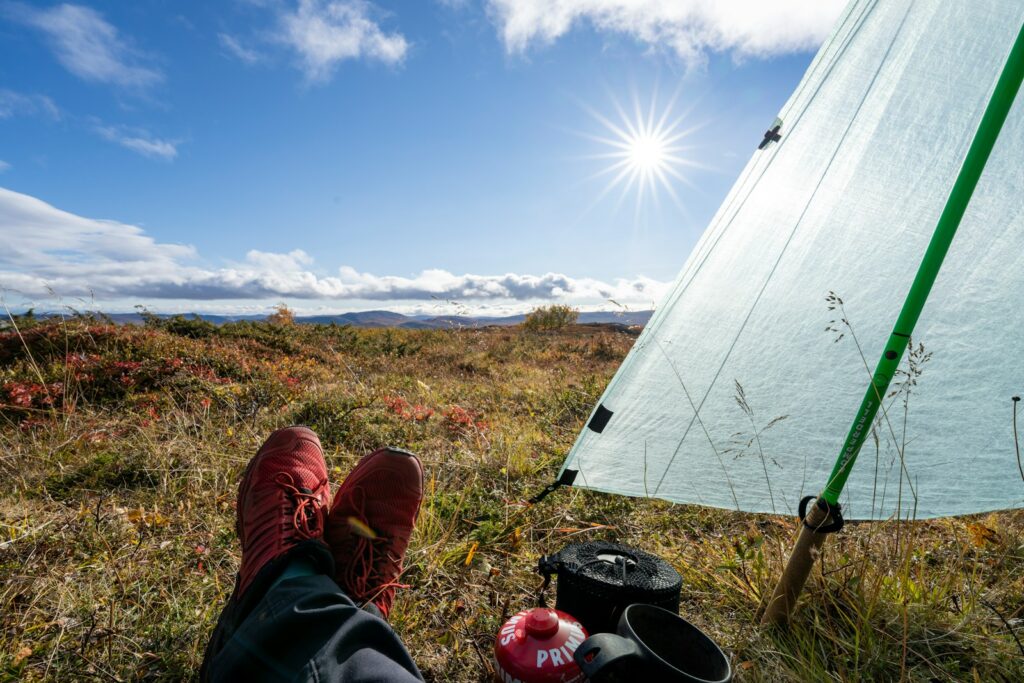 person in black pants and red shoes sitting near white tent during daytime